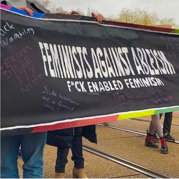 Een zwarte banner waarop staat / a black banner which says: feminists against ableism. F*ck enabled feminism